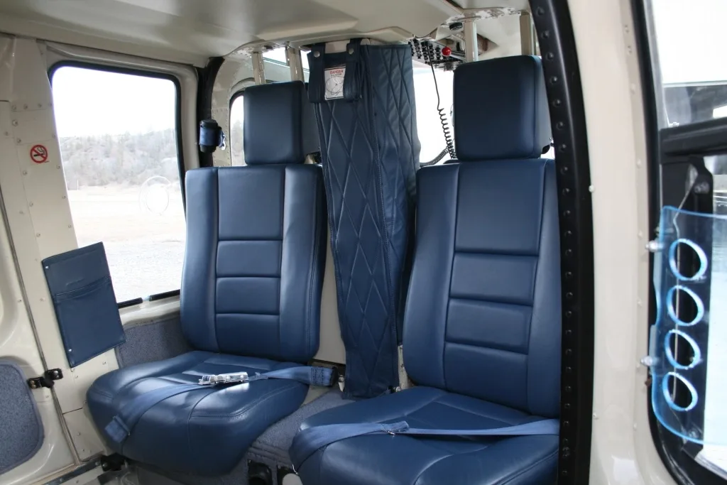 View of the blue leather passenger seats in the helicopter cabin, looking towards the rear.