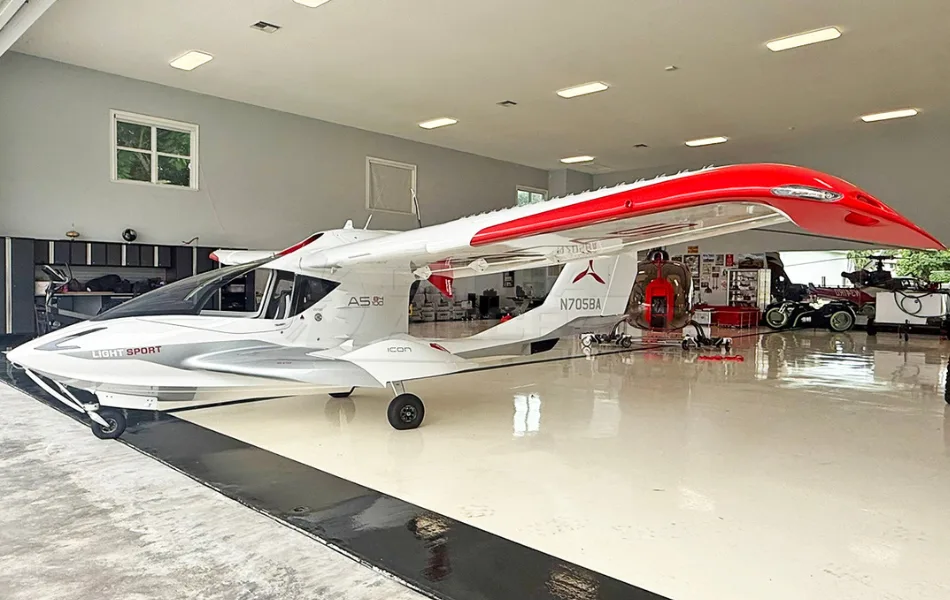 A white and red ICON A5 amphibious light sport aircraft is parked inside a clean hangar.