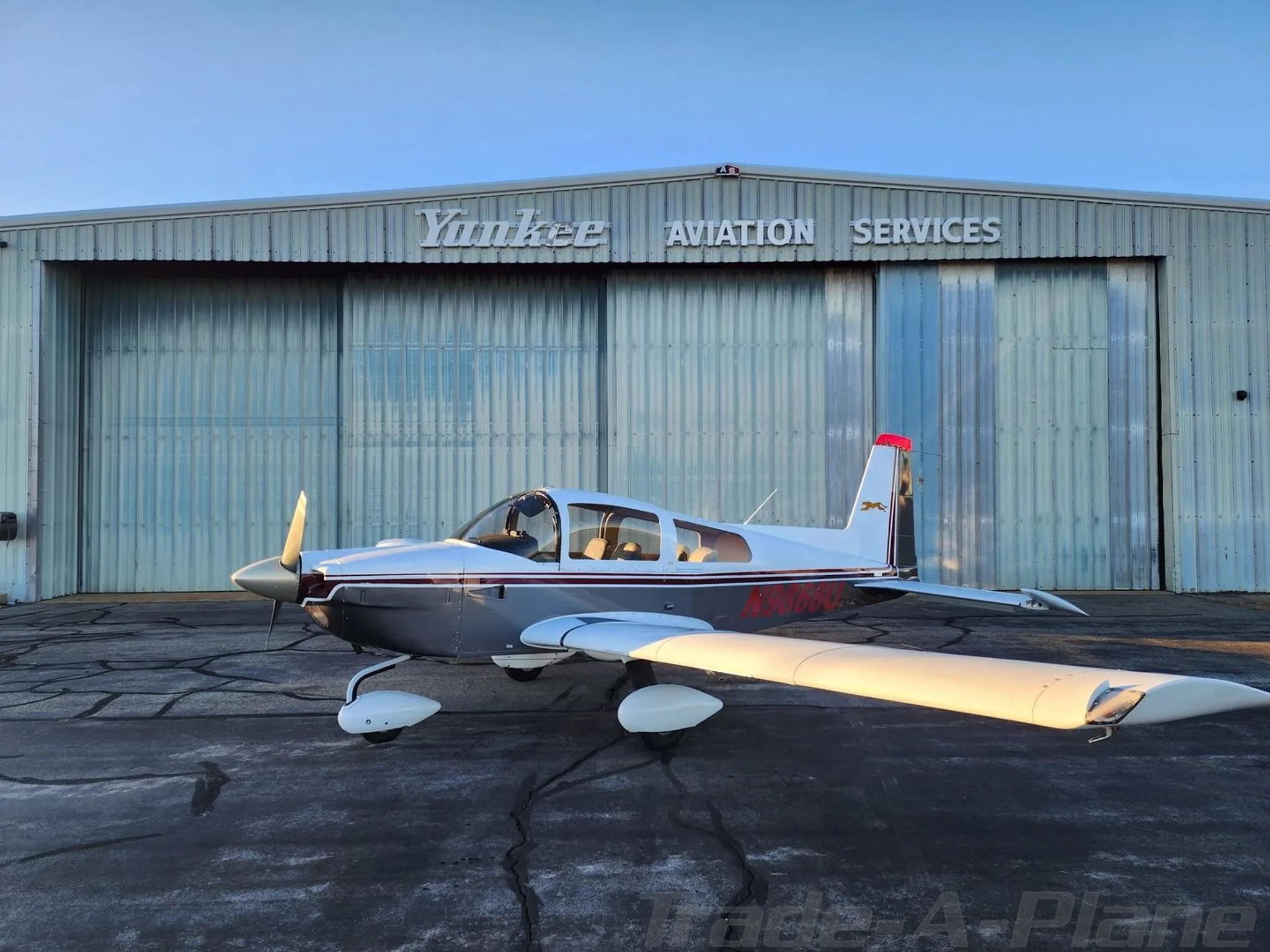 A side view of the aircraft in front of a hangar.