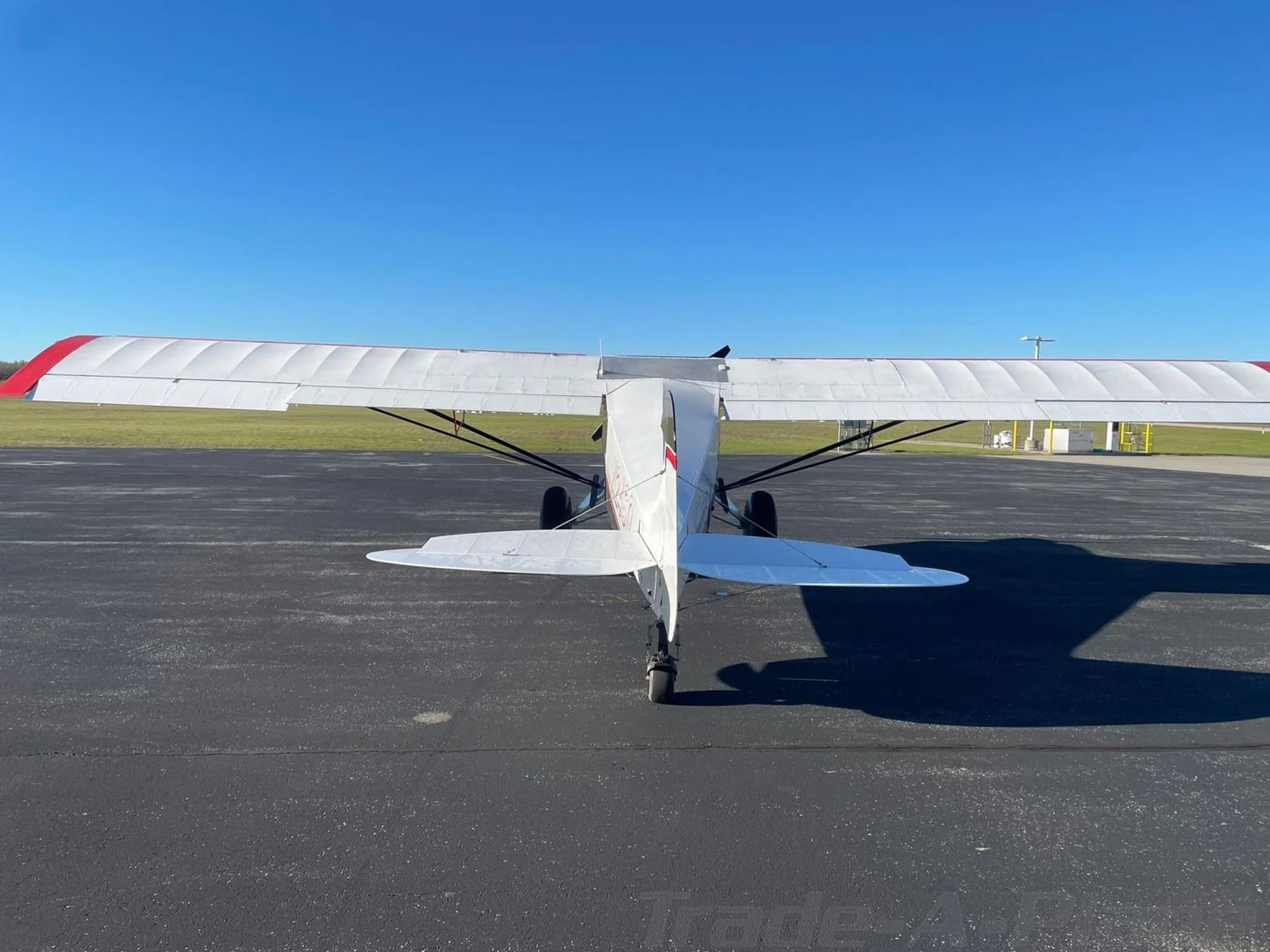 A rear view of the white, black, and red STOL Quest 4 aircraft (N24SQ) parked on an asphalt tarmac.