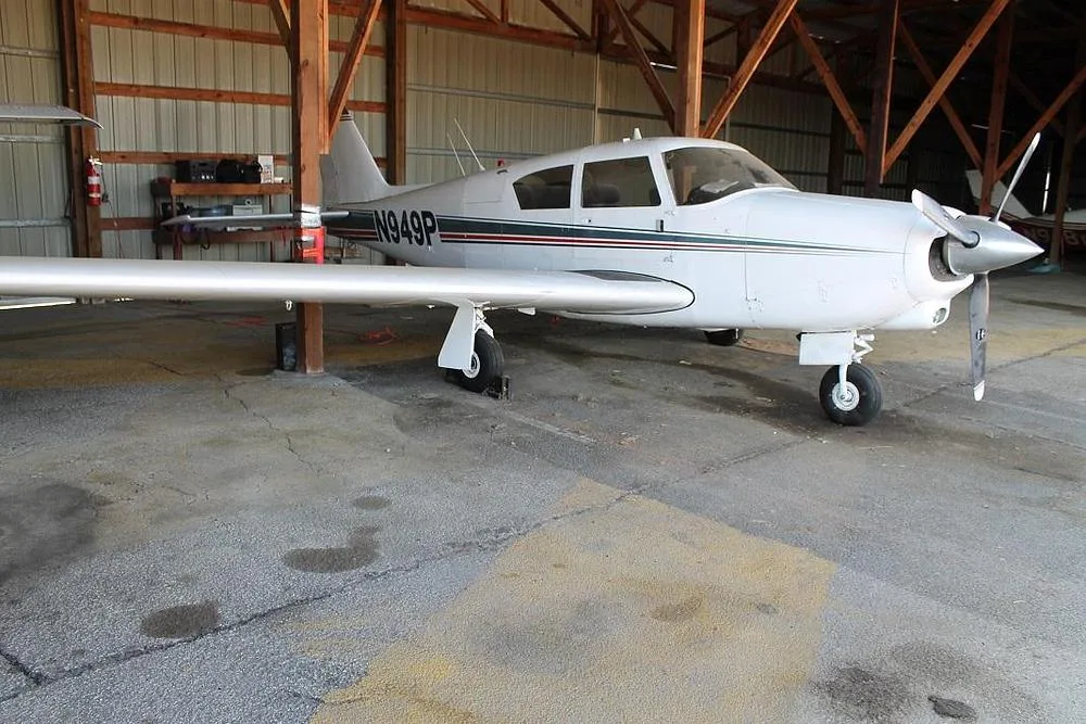 A white single-engine propeller aircraft, N949P, with green and red stripes, parked in a hangar.
