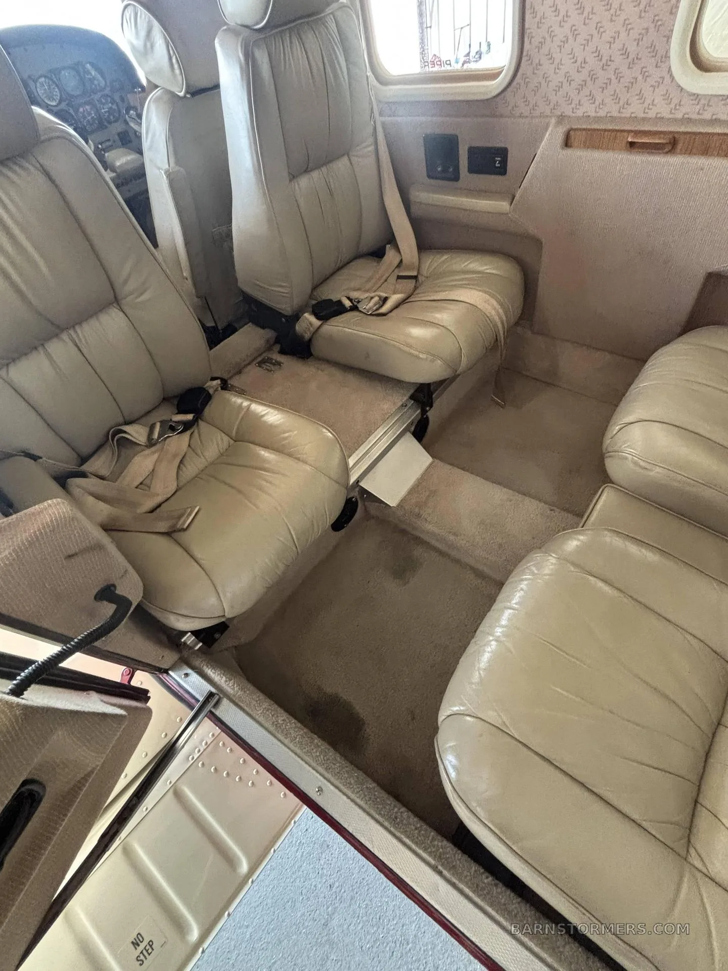 The rear light tan leather passenger seats in the cabin of a Piper Saratoga II HP aircraft.