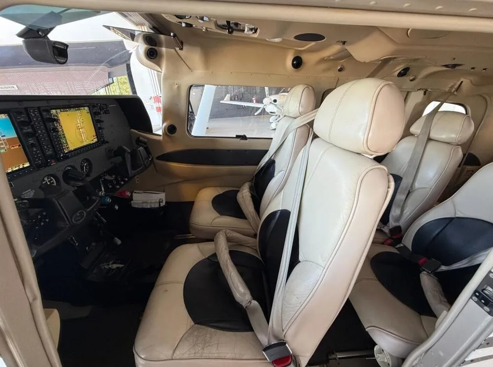 The cockpit and front passenger seats of a Cessna 206 Stationair, showing the instrument panel and cream-colored leather seats.
