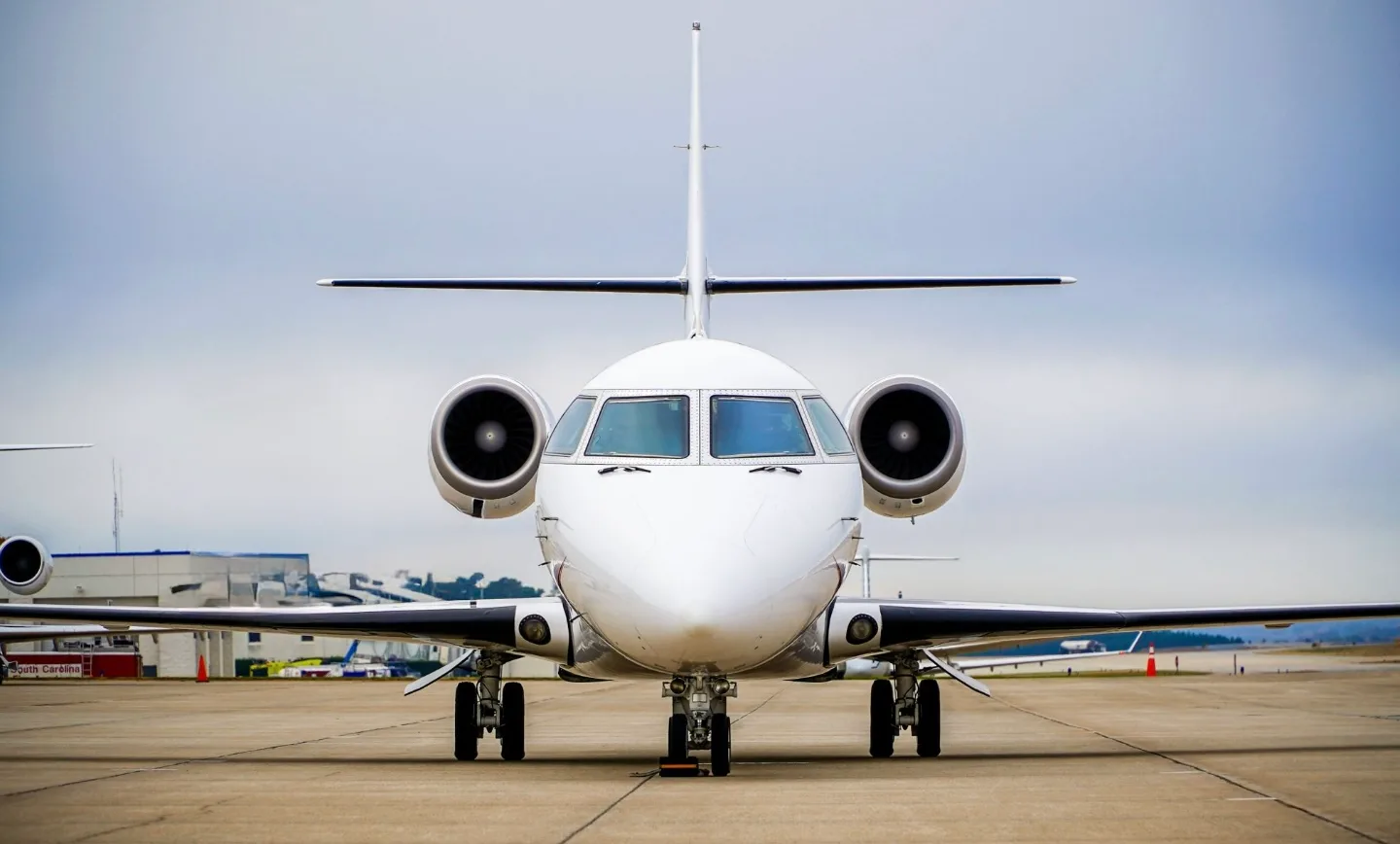 A business jet is shown head-on on the runway.