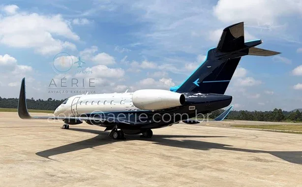 A rear view of the white and dark blue Embraer Praetor 600 business jet parked on a tarmac.