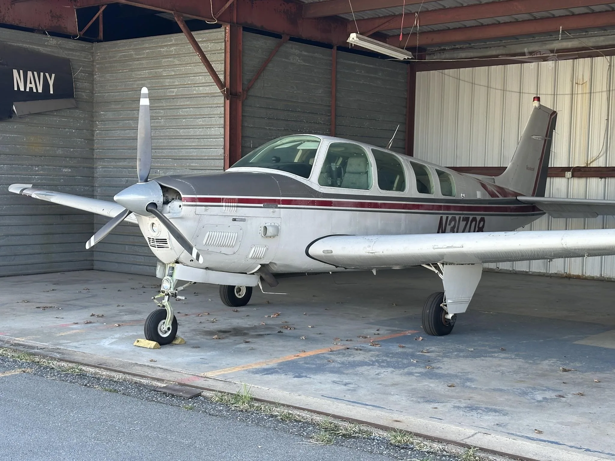 A silver and maroon twin-engine Beechcraft aircraft, registration N31708, parked inside a hangar.