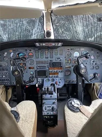 View of a cockpit instrument panel with two yokes and sunshades on the windshield.