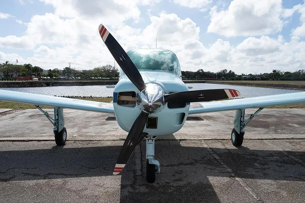 A close-up front view of the light blue single-engine propeller aircraft, N9207S, showing its propeller and nose gear.