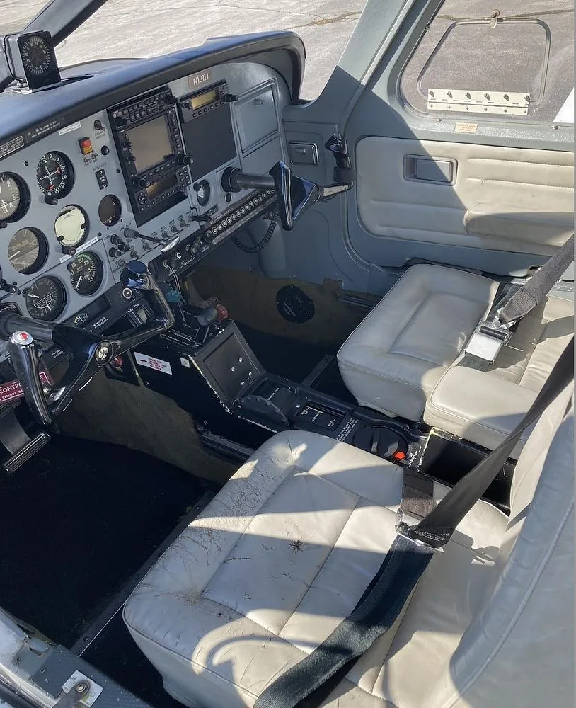 The cockpit and front cabin of the aircraft, showing the instrument panel, controls, and light-colored seats.