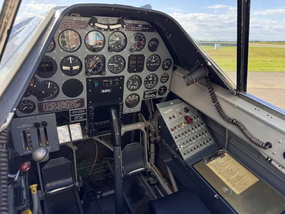 The cockpit of a North American T-6 Texan aircraft, showing the instrument panel, controls, and "N4PC" on a placard.