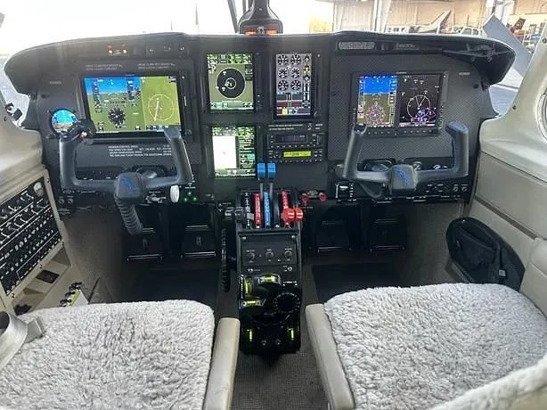 The cockpit of an aircraft featuring a modern glass panel with multiple digital displays and two control yokes.