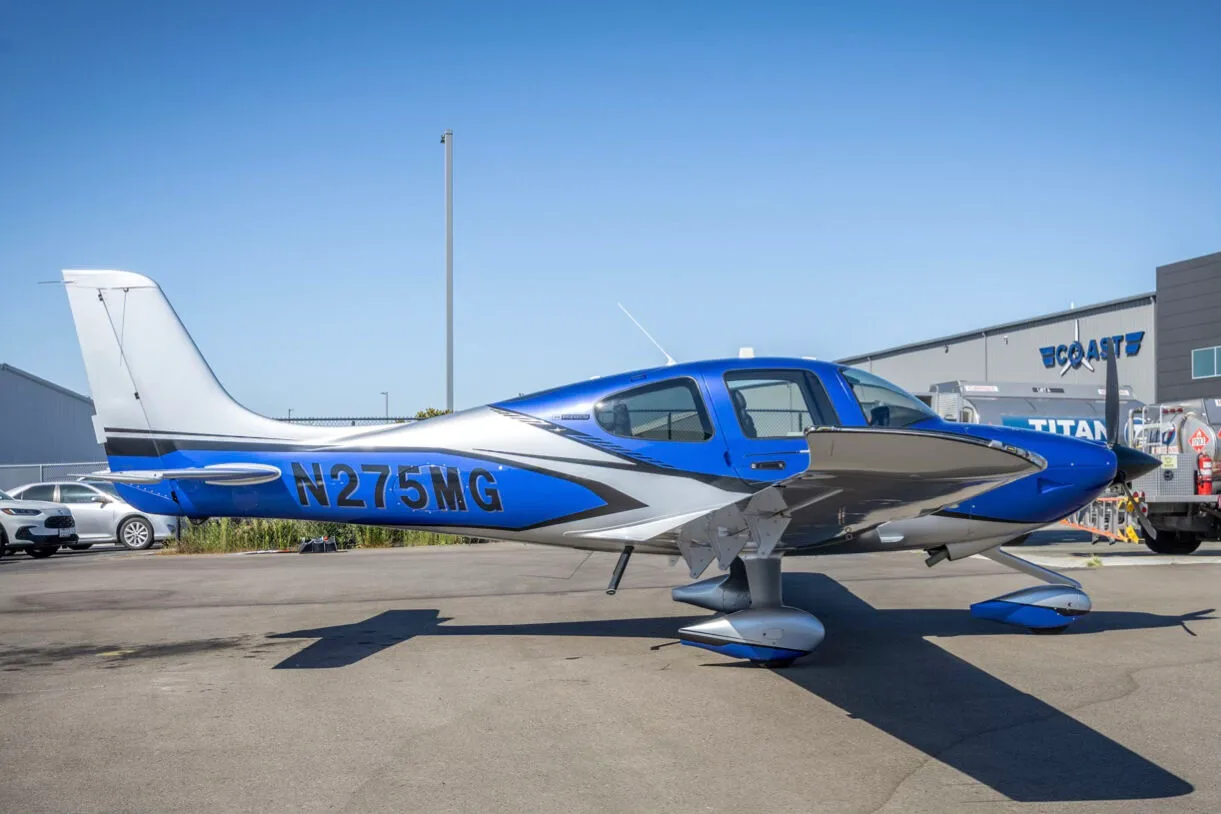 A blue and silver Cirrus SR22 aircraft, N275MG, parked on an airport tarmac.