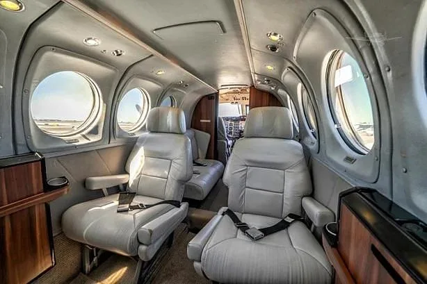 A different angle of the aircraft's interior cabin shows light gray leather seating and wood trim.