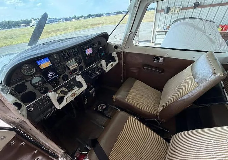 The aircraft's cockpit and front cabin interior, featuring brown and striped seats and a detailed instrument panel.