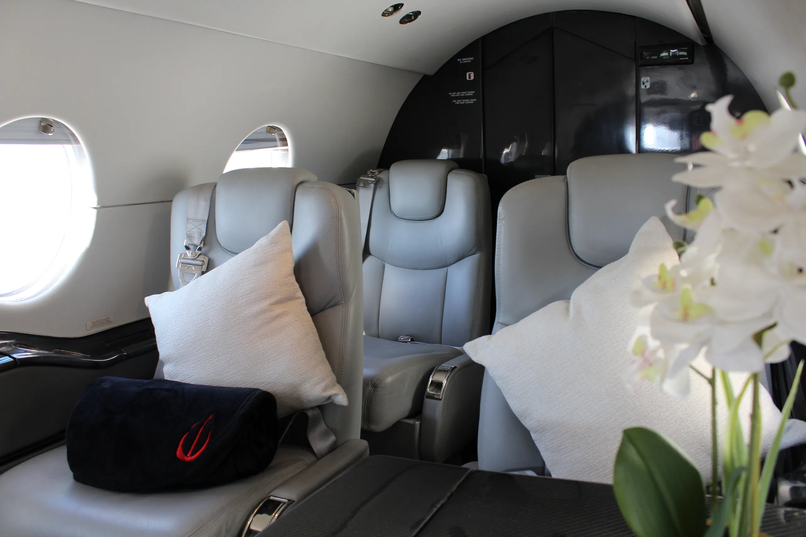 Interior of the aircraft cabin with gray leather seats and a view of the window.