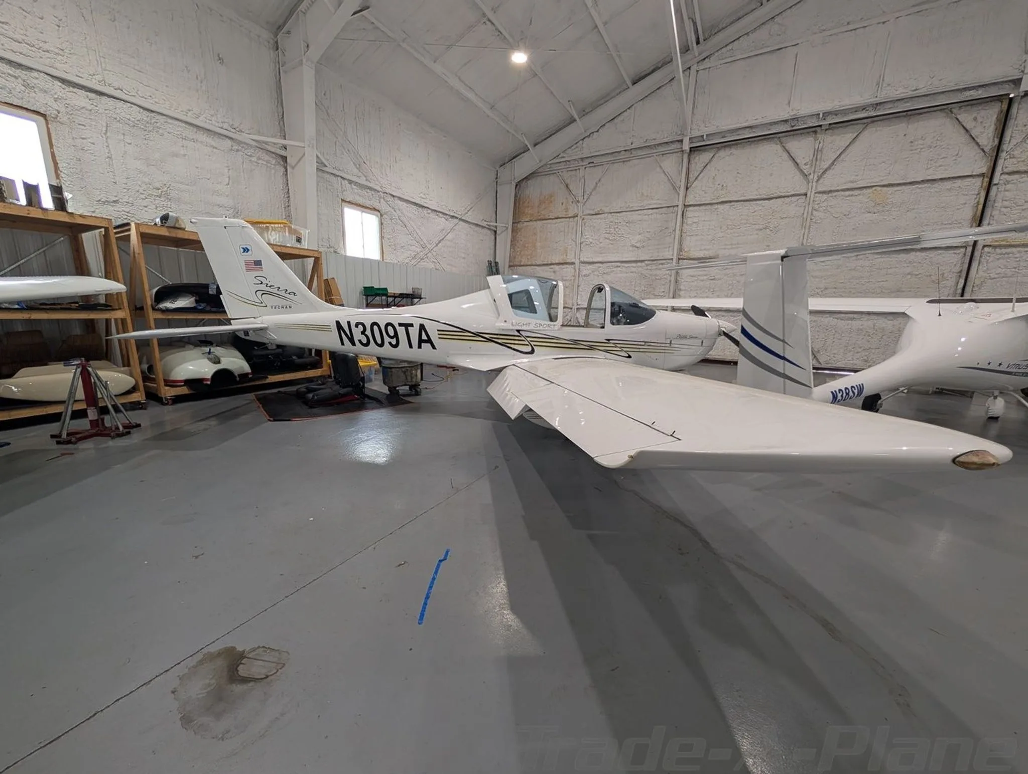A three-quarter rear view of the white Tecnam P2002 Sierra N309TA parked in a hangar.