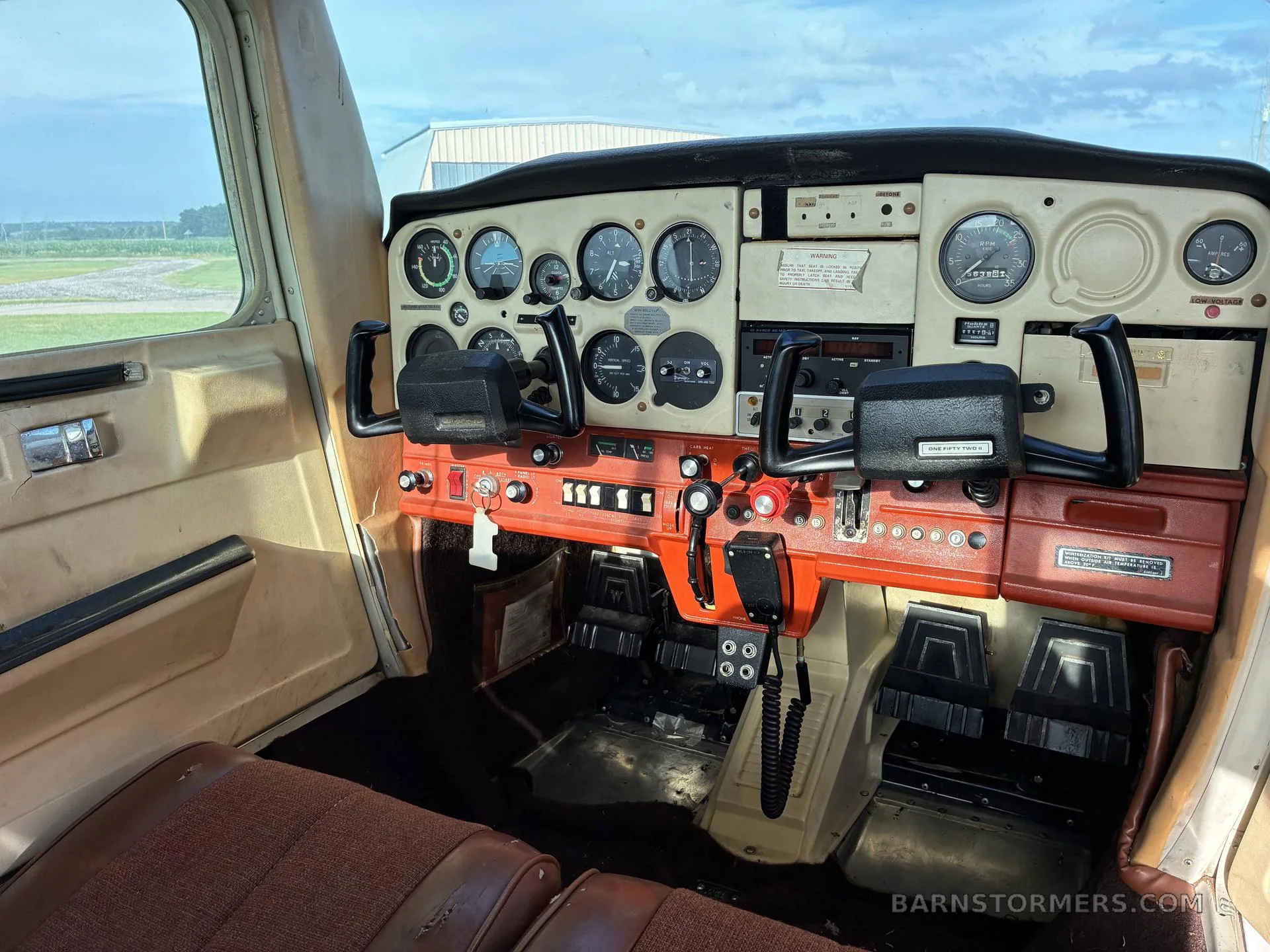 The cockpit of a Cessna 172 shows the instrument panel, yokes, and orange control console.