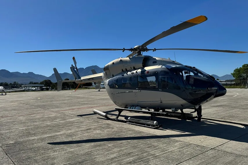 A light gray and black helicopter on the tarmac.
