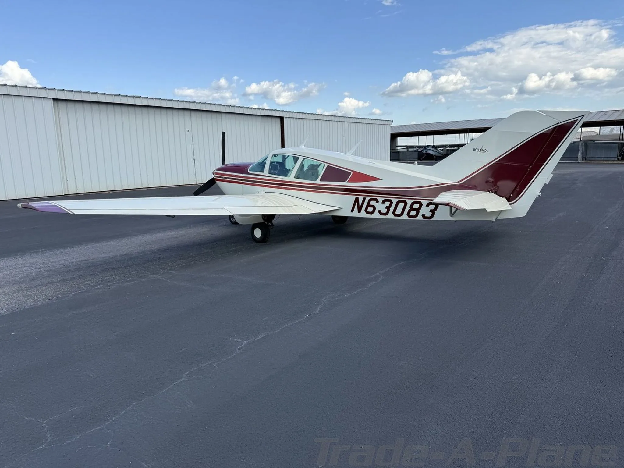 Rear-side view of a white and maroon Bellanca Viking N63083 parked on a tarmac.