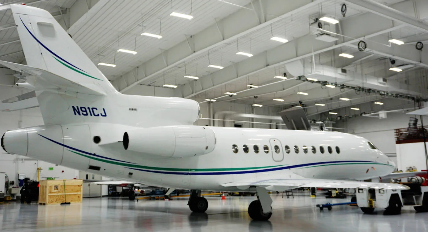 A Falcon 900 aircraft with registration N91CJ is parked inside a hangar.