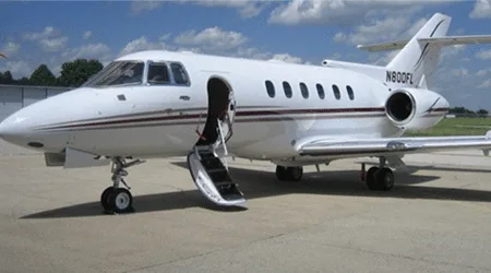 White jet with open door parked on the tarmac.