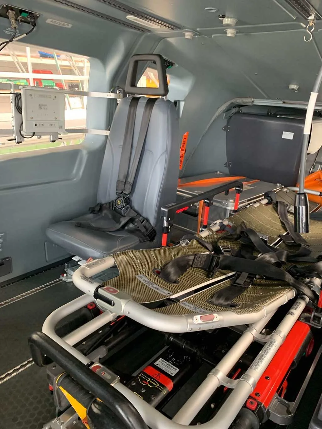 The interior cabin of a helicopter, showing an EMS configuration with a stretcher and a single crew seat.