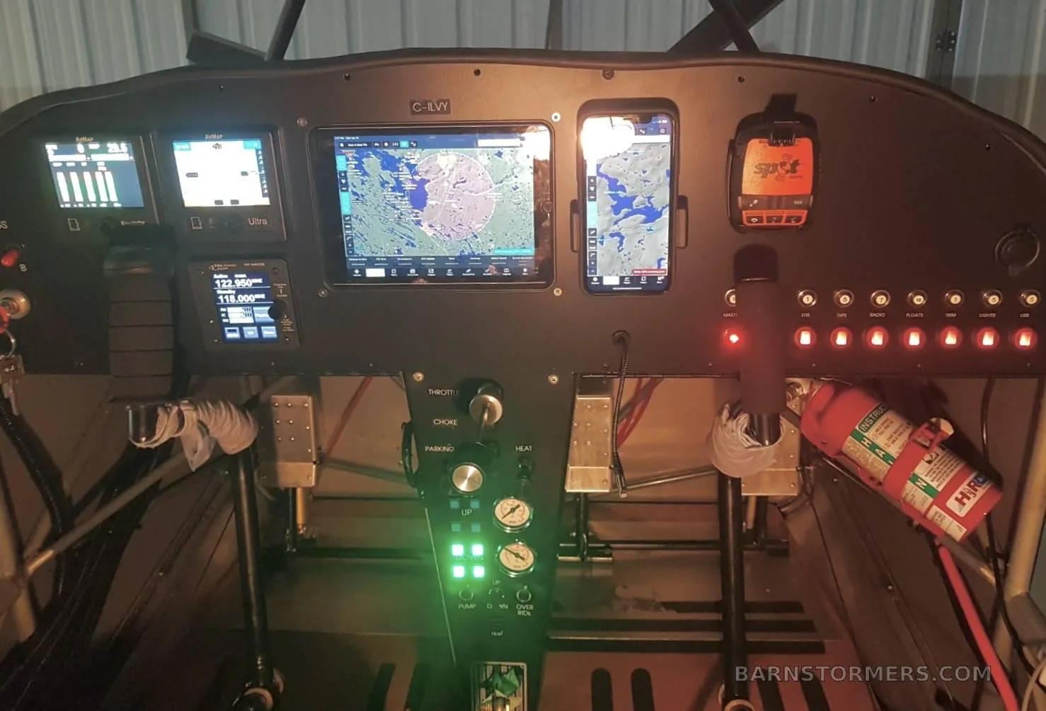 The cockpit instrument panel of a C-ILVY aircraft, showing multiple digital displays, controls, and a fire extinguisher.