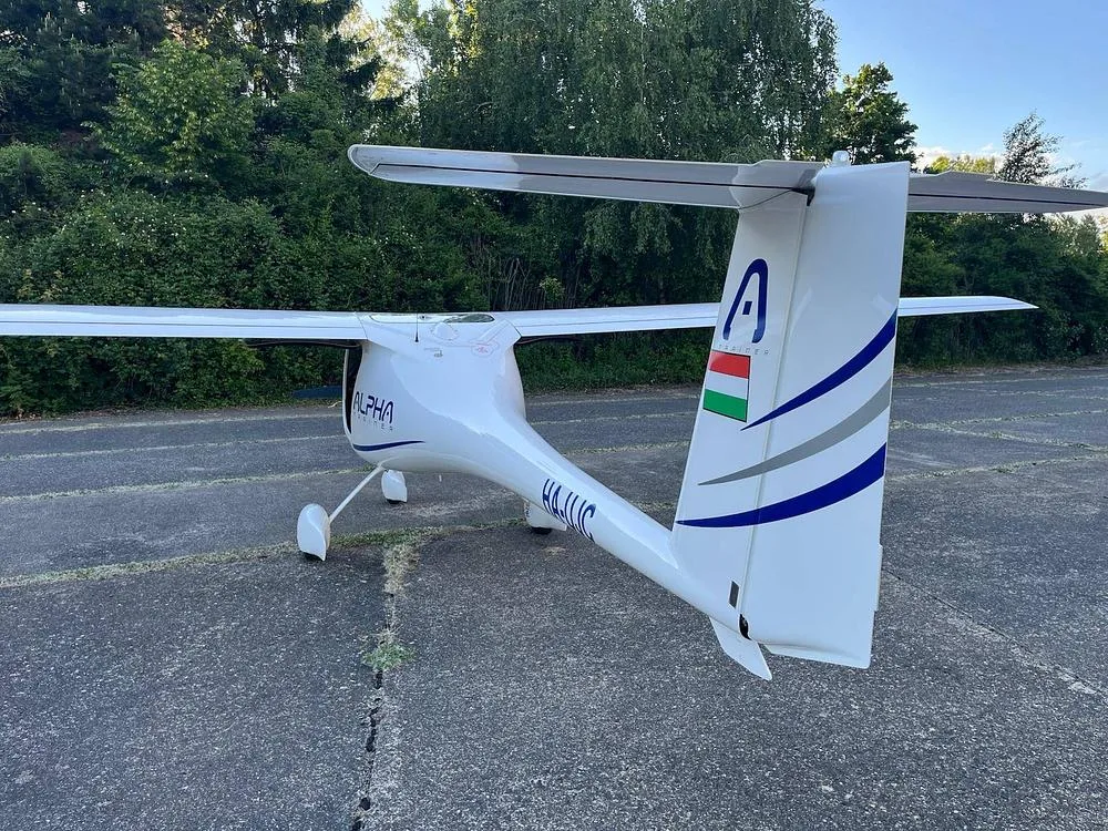 Rear view of a white Alpha Light Sport aircraft, showing the tail with Hungarian flag and registration HA-LUC.