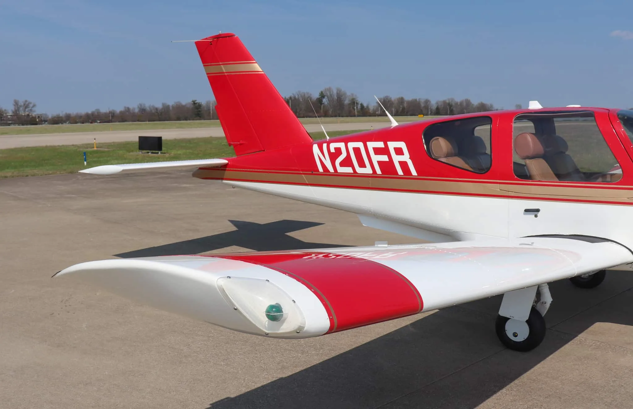 A close-up view of the tail and right wingtip of a red and white Socata Trinidad aircraft, showing the N-number.