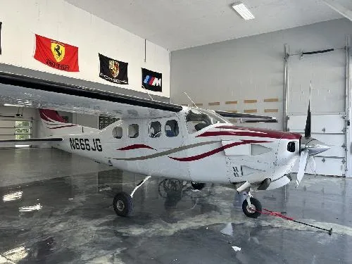 A Cessna 208 Caravan with a white and red paint scheme is parked in a hangar.