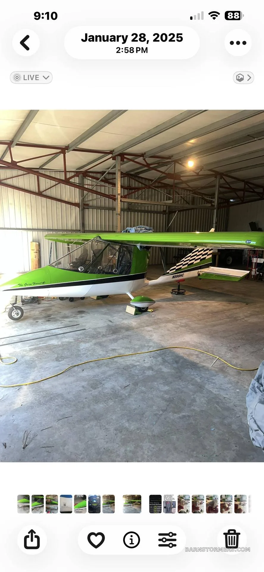 A bright green and white ultralight aircraft with a checkered tail is parked inside a hangar.