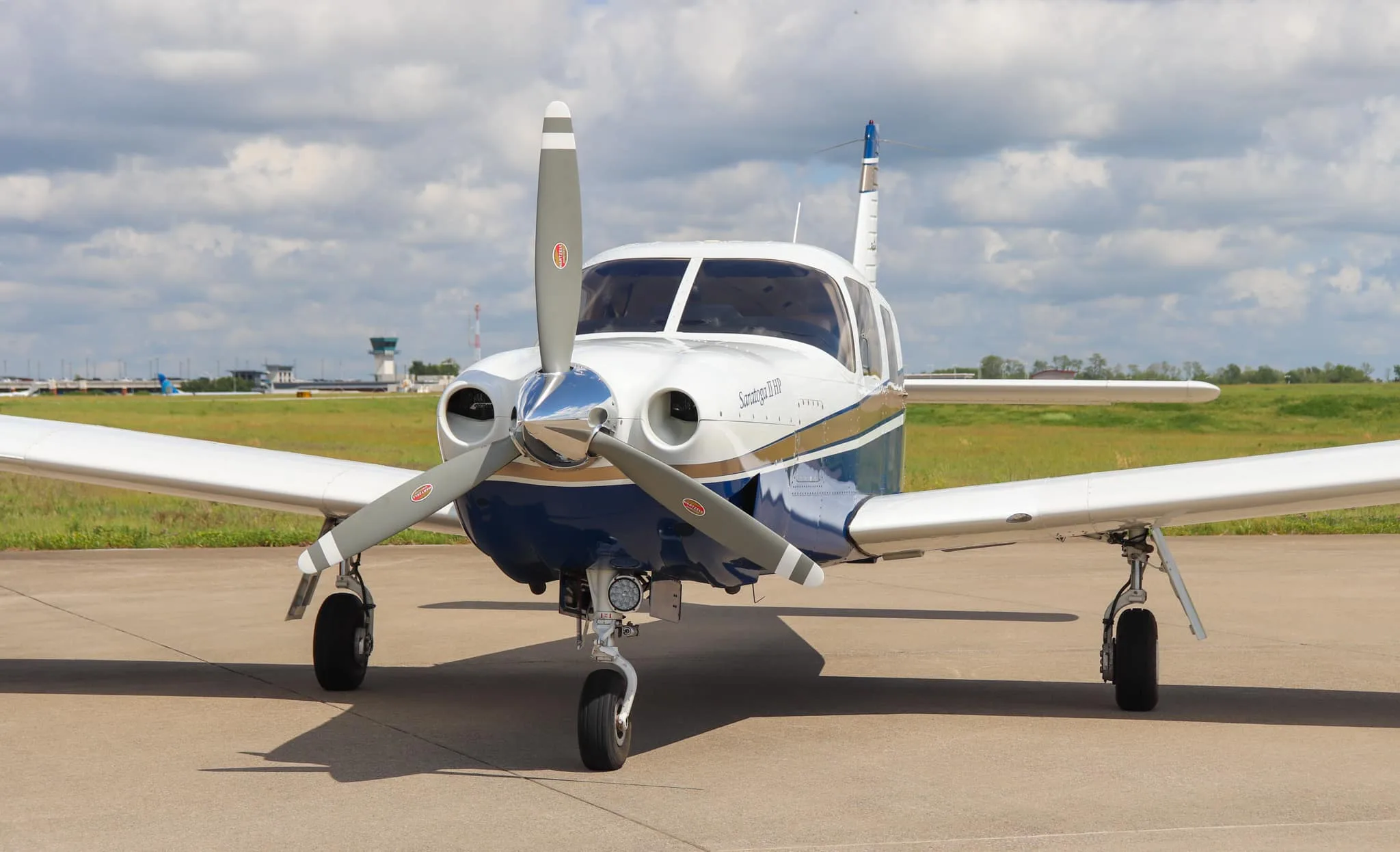 A front three-quarter view of the Piper Saratoga II HP aircraft, N954K, on an airfield under a cloudy sky.
