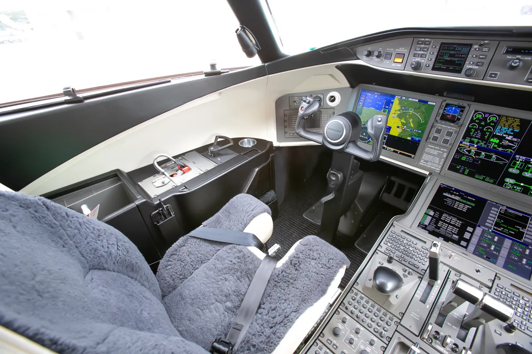 A close-up view of the pilot's seat and the right side of a modern aircraft cockpit with digital displays.