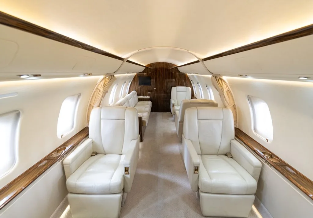 A close-up view of the fuselage, windows, and engine of a white Bombardier Challenger jet.
