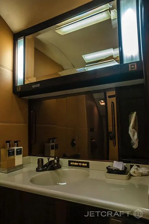 A lavatory sink with a mirror and toiletries inside a business jet.