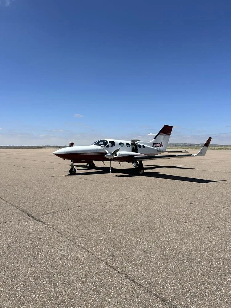 A white and red Cessna 340A twin-engine aircraft with registration N902BA parked on an asphalt runway under a clear blue sky.