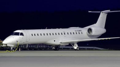 Side view of a white Embraer Legacy 600 aircraft on the tarmac at night.