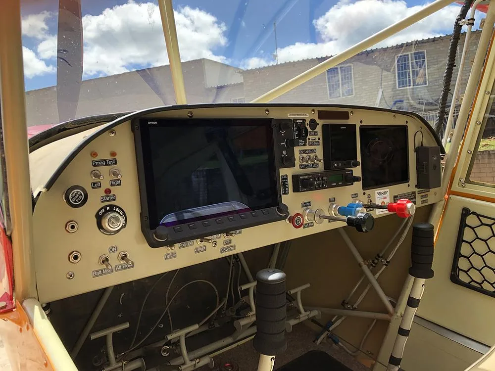 The cockpit features a large digital display, various switches, and control sticks in a light-colored panel.