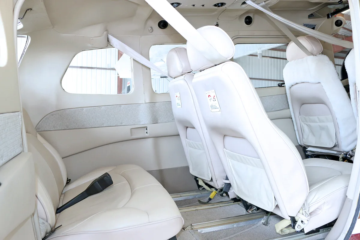 The beige leather interior cabin of the aircraft, showing multiple passenger seats with seatbelts.