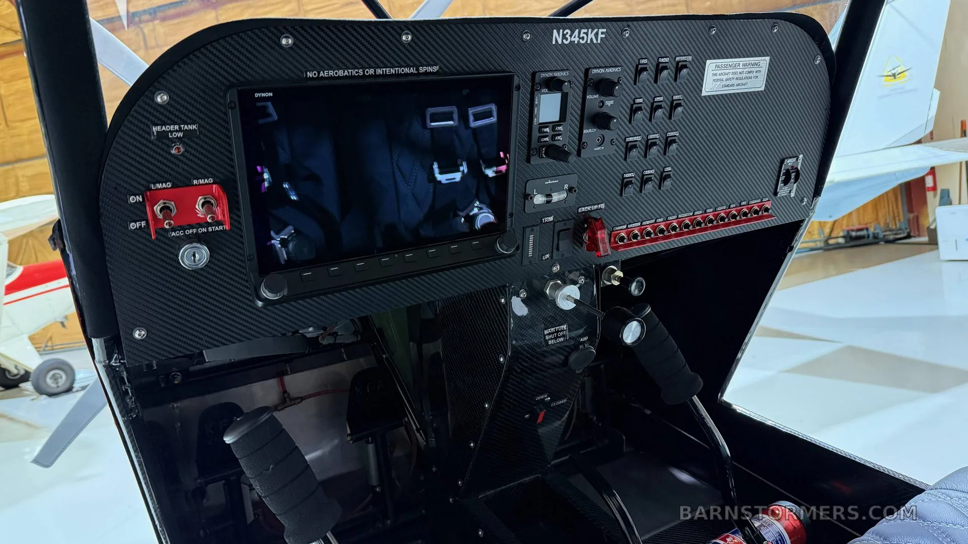 The modern carbon fiber instrument panel of a Kitfox aircraft, featuring a large digital display and various switches.