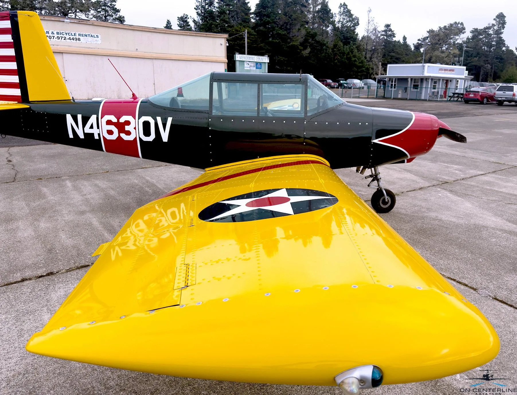 A close-up view of the N4630V aircraft's yellow wing with a US star insignia, and the black and red fuselage.