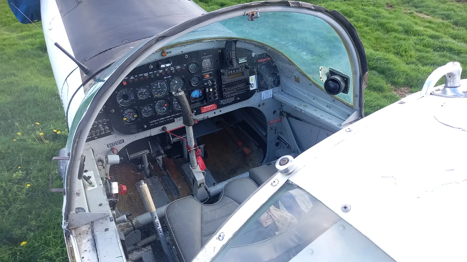An overhead view of the aircraft's cockpit, showing the instrument panel, controls, and worn seats.