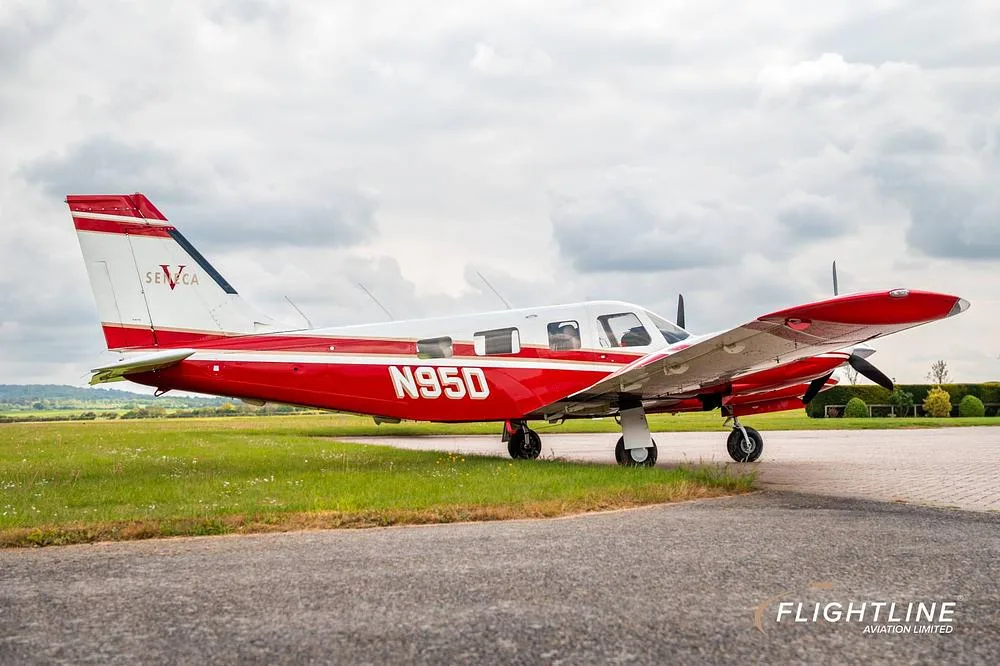 A red and white Piper Seneca aircraft with registration N95D parked on a paved surface, viewed from the right side.