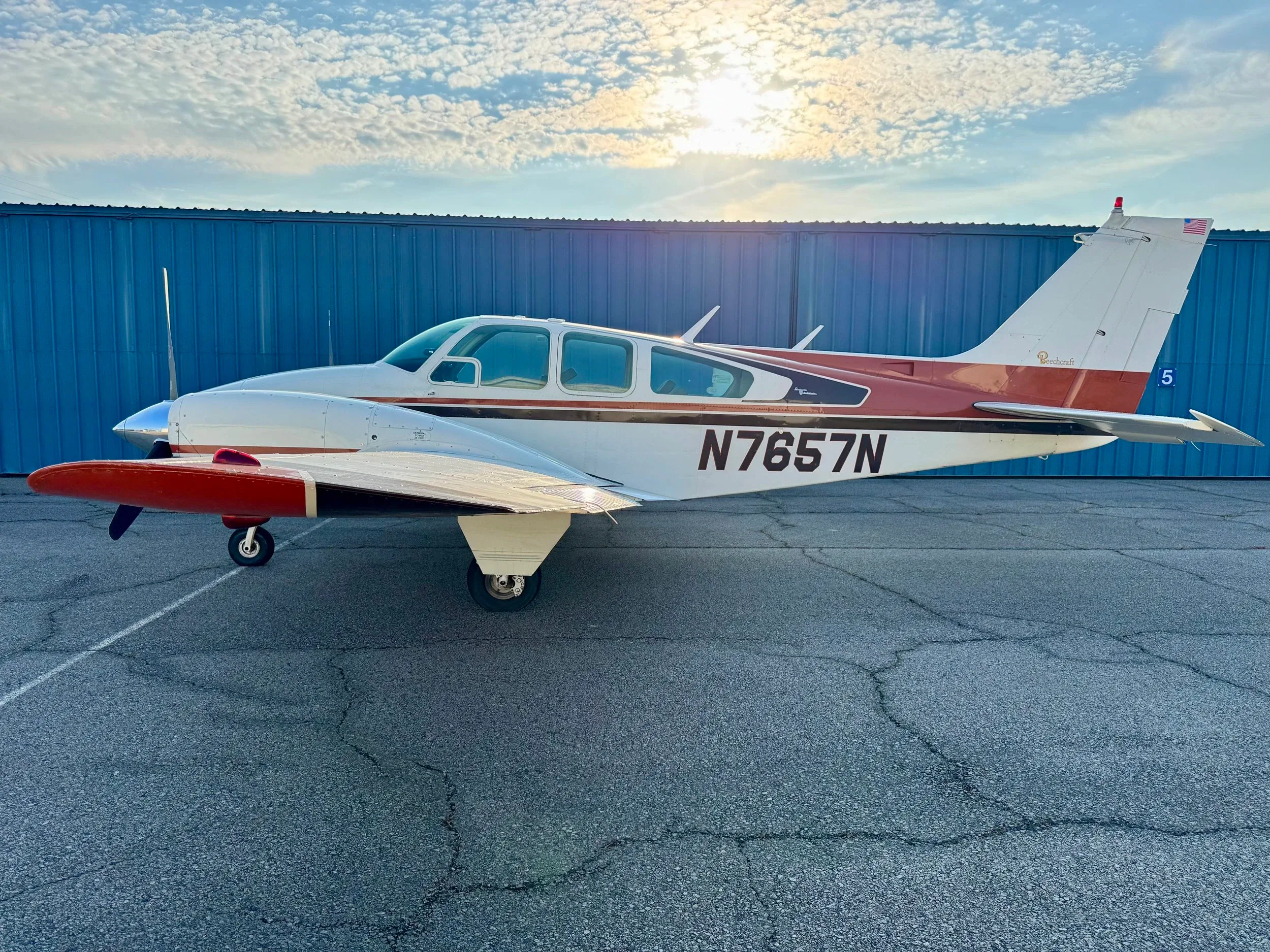 A Beechcraft Baron B55 aircraft with a white and brown paint scheme parked on the tarmac.