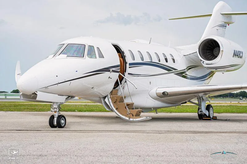 A close-up view of the front left side of the Cessna Citation XLS+ business jet N448CX, showing the open main cabin door with stairs extended.