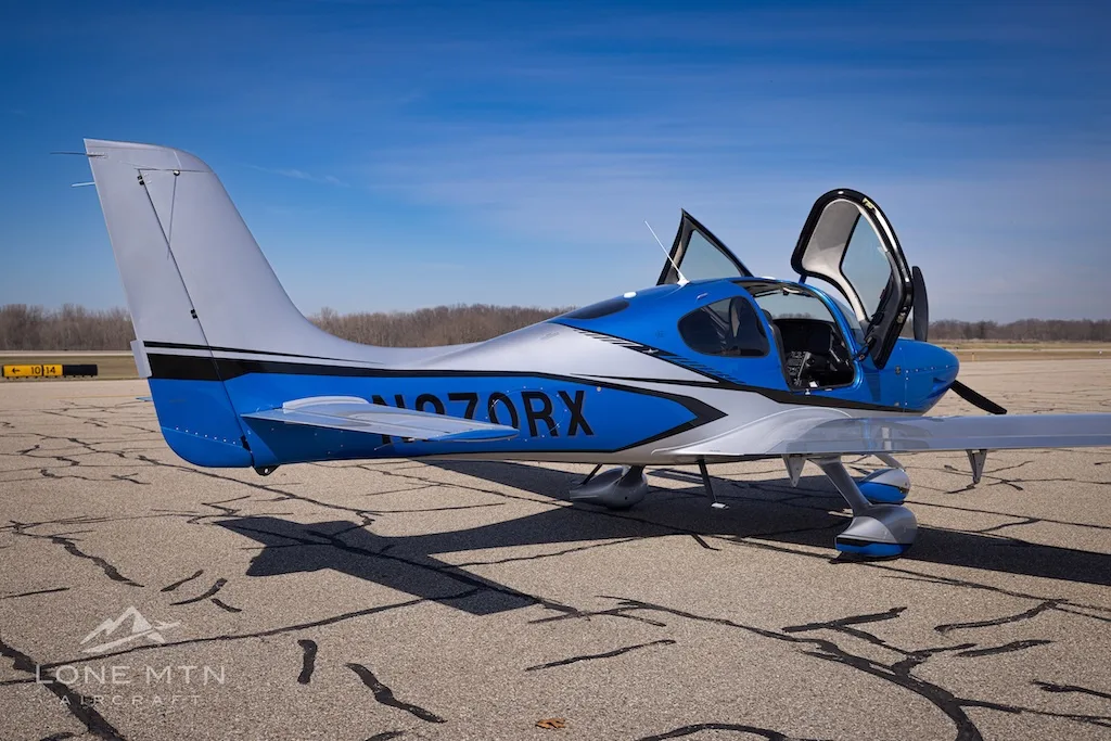 A three-quarter rear view of the blue and silver Cirrus SR20 aircraft, registration N270RX, parked on an airport tarmac.