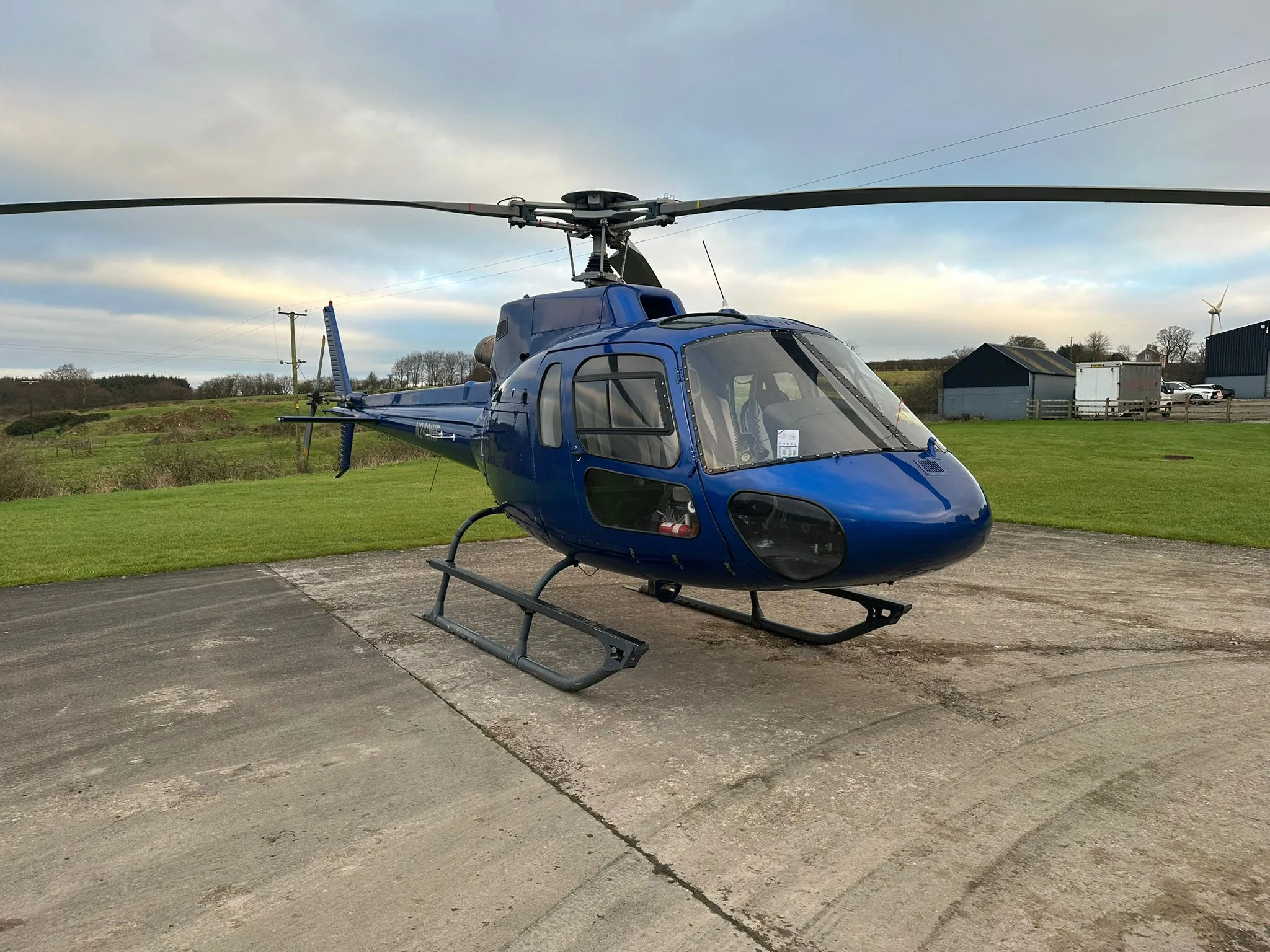 N240WF helicopter parked on a concrete pad with grass in the background.
