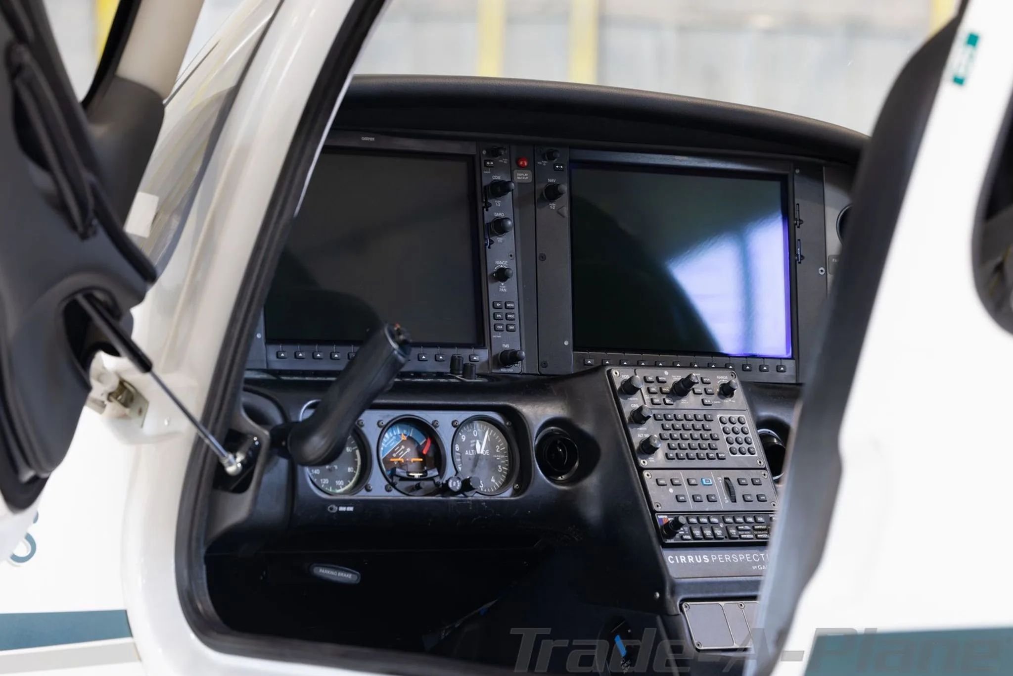 A close-up view of the Cirrus SR22 cockpit instrument panel with two large display screens and various controls.