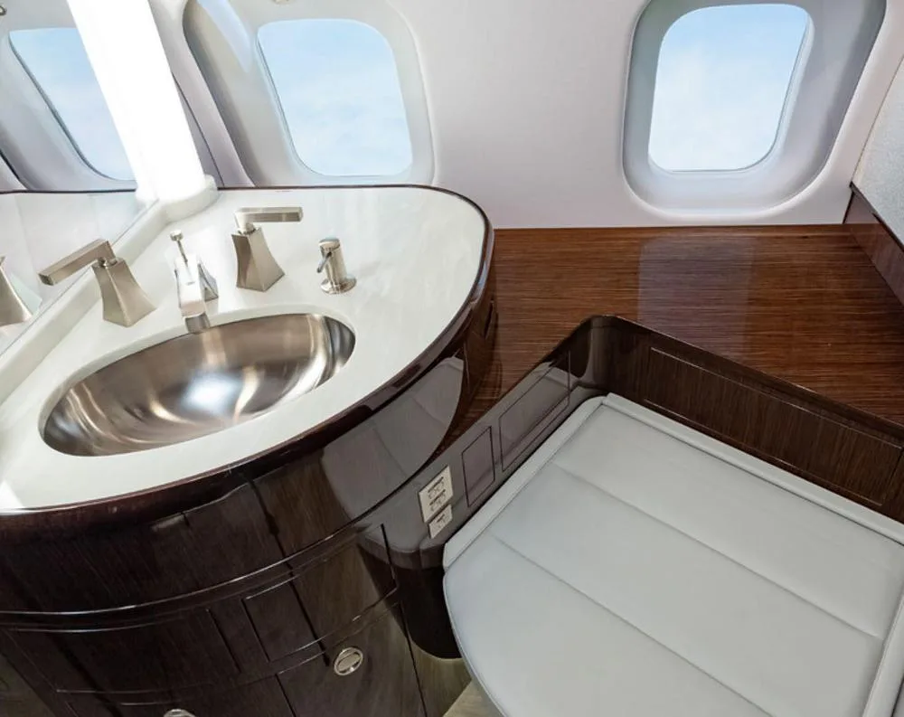 A luxurious aircraft lavatory with a modern sink, chrome fixtures, and large windows.