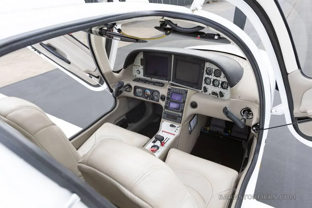 An overhead view into the open cockpit of a Cirrus SR22 reveals the instrument panel and front seats.